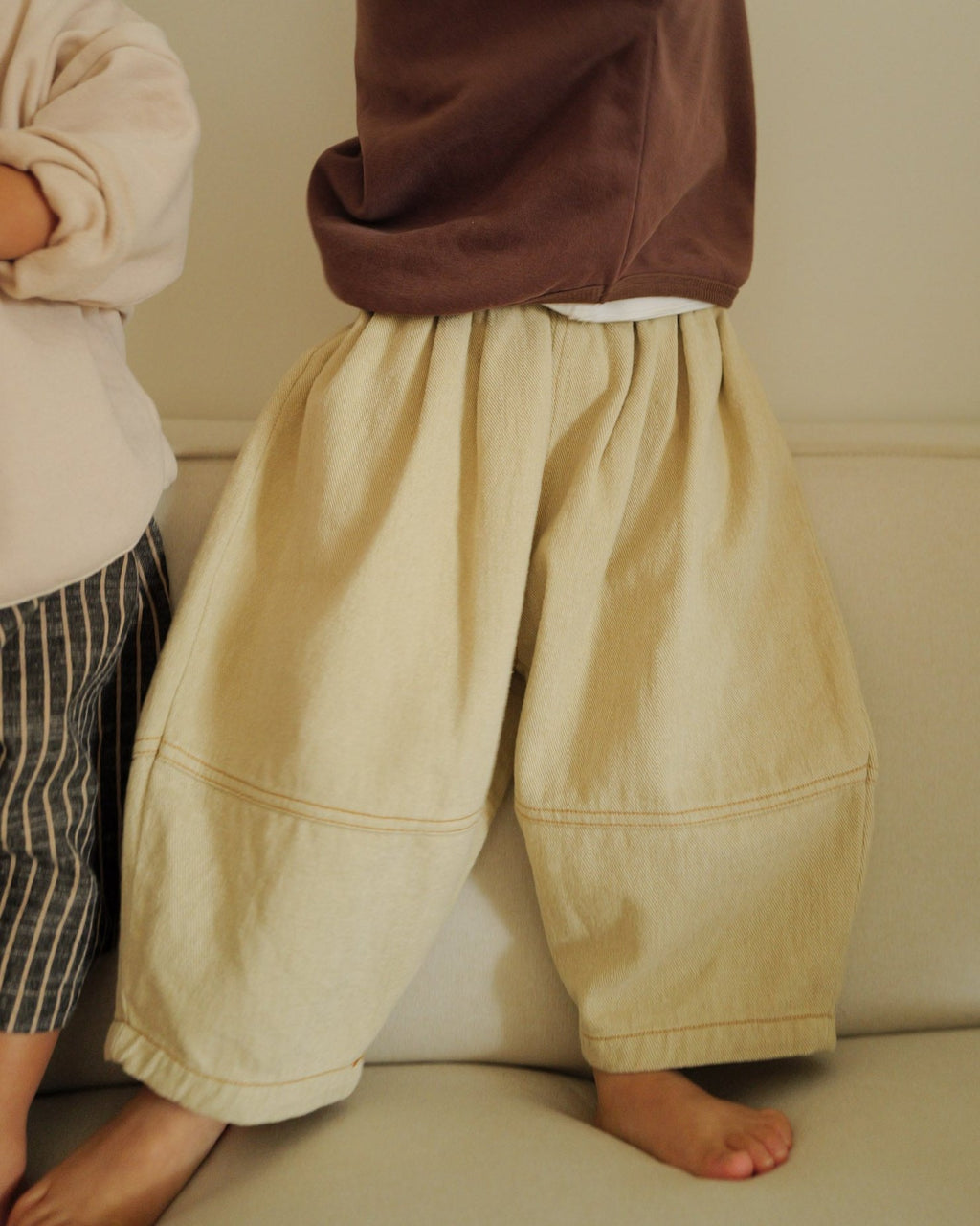 boy standing on couch wearing barrel pant