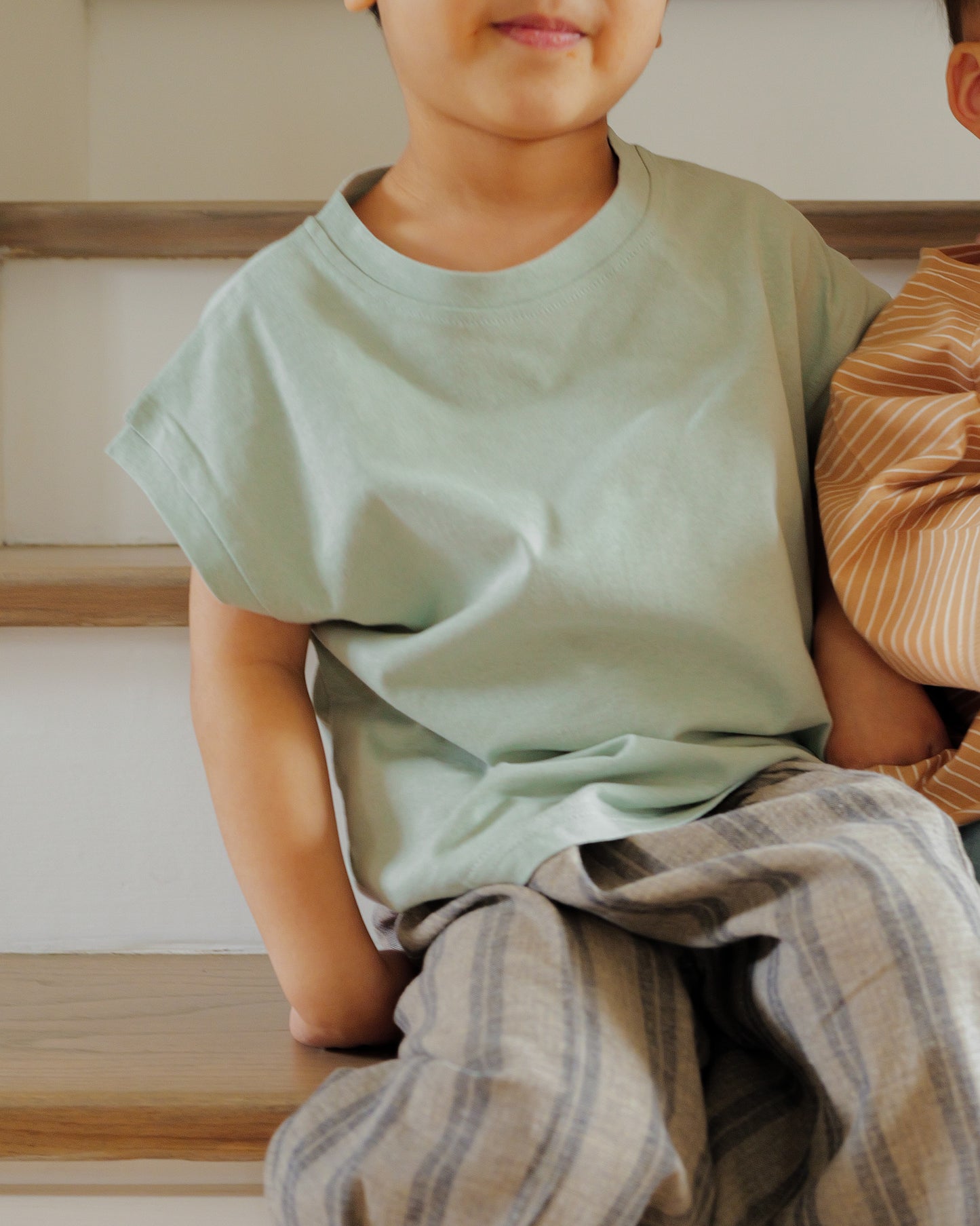 boy sitting in cut off tee sage